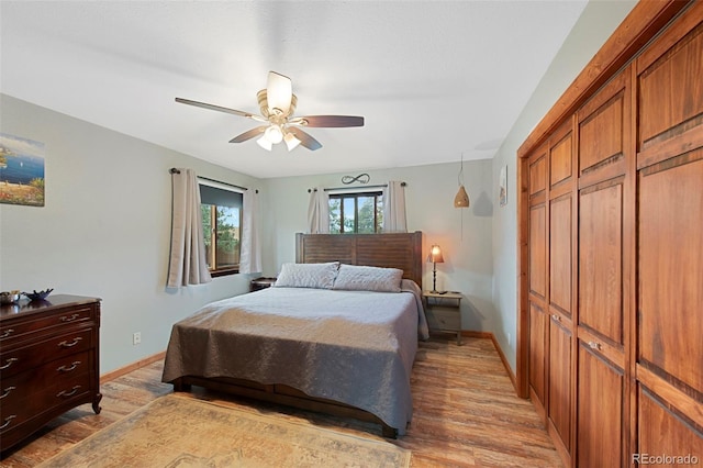 bedroom with light wood-type flooring, baseboards, a ceiling fan, and a closet