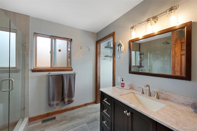 bathroom featuring a shower stall, wood finished floors, vanity, and baseboards