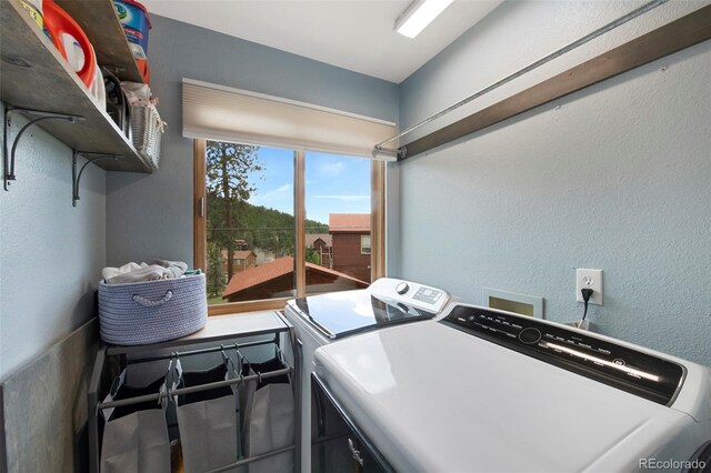 laundry room featuring washer and clothes dryer and a textured wall