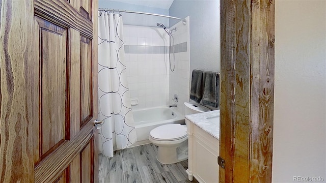 full bathroom with wood finished floors, toilet, shower / bath combination with curtain, and vanity