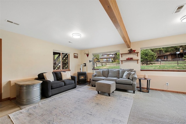 living room with a wood stove, baseboards, and beamed ceiling