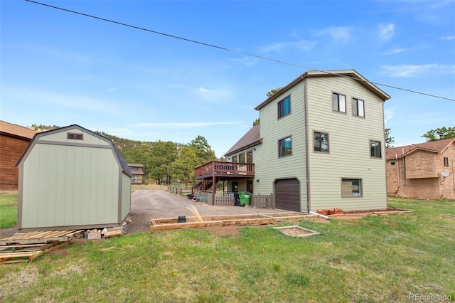 rear view of property with a storage unit, a wooden deck, an attached garage, a lawn, and an outdoor structure