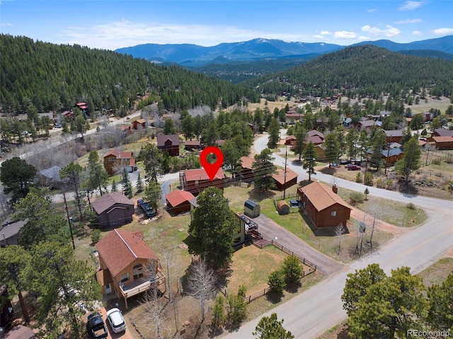 aerial view of residential area with a mountain backdrop and a heavily wooded area