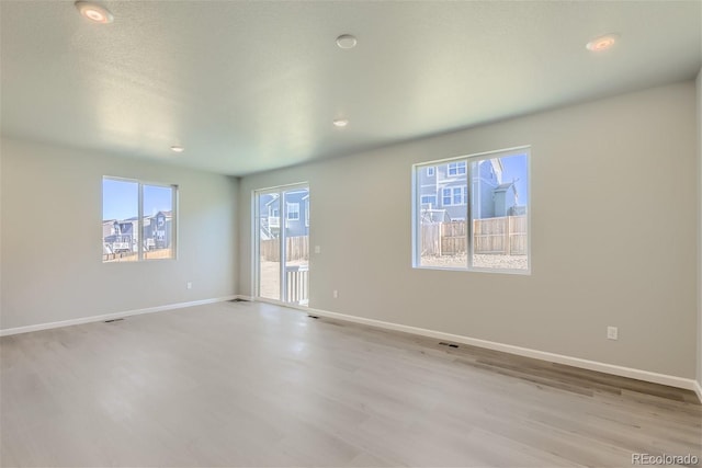 spare room with a textured ceiling and light hardwood / wood-style floors