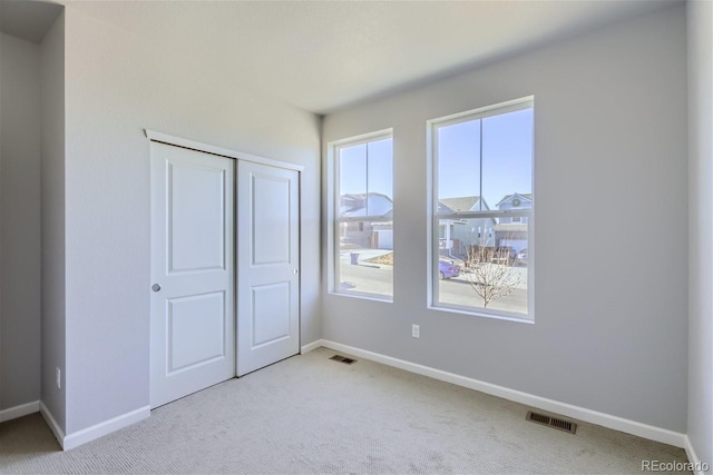 unfurnished bedroom with a closet and light carpet