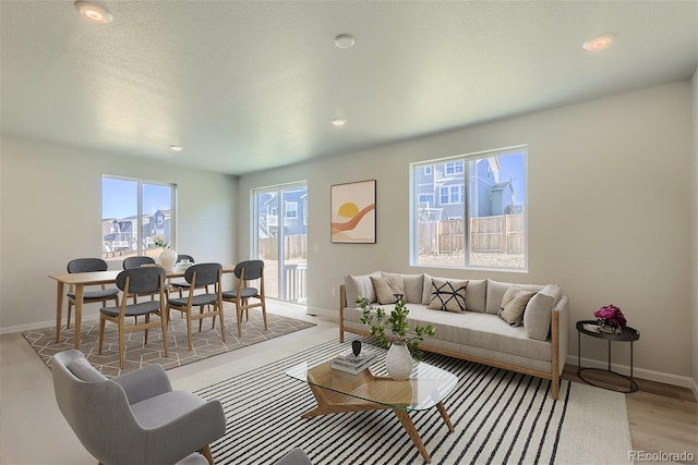 living room with a wealth of natural light, a textured ceiling, and light hardwood / wood-style flooring