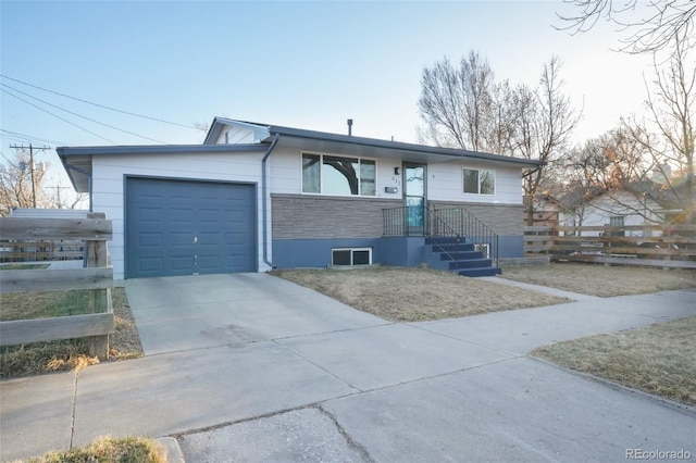 view of front of home featuring driveway, an attached garage, and fence