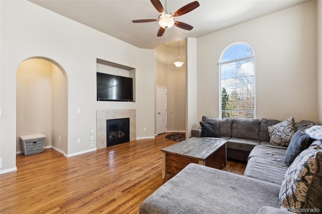 8913 Sunstone Dr, Colorado Springs, CO 80924 - living room with ceiling fan, wood finished floors, arched walkways, a tile fireplace, and baseboards