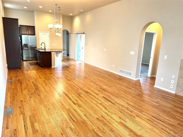 8913 Sunstone Dr, Colorado Springs, CO 80924 - kitchen featuring stainless steel fridge with ice dispenser, open floor plan, light wood finished floors, dark countertops, and a high ceiling