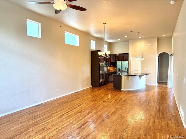 8913 Sunstone Dr, Colorado Springs, CO 80924 - kitchen with open floor plan, arched walkways, dark countertops, appliances with stainless steel finishes, and a breakfast bar area