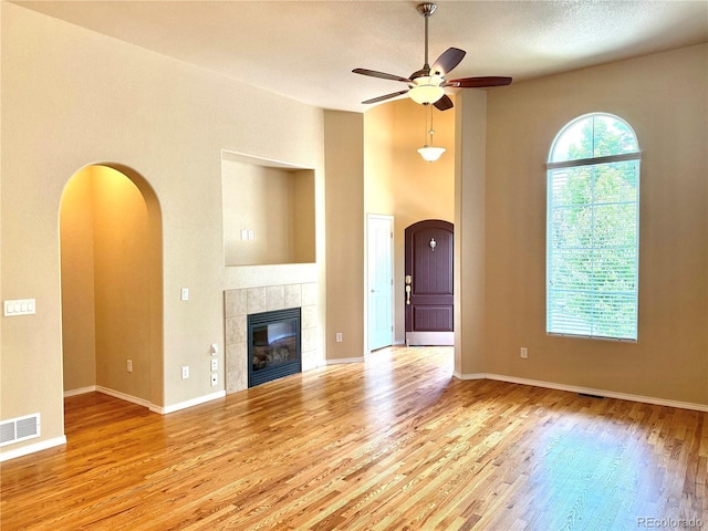 8913 Sunstone Dr, Colorado Springs, CO 80924 - unfurnished living room with ceiling fan, wood finished floors, arched walkways, a tiled fireplace, and baseboards