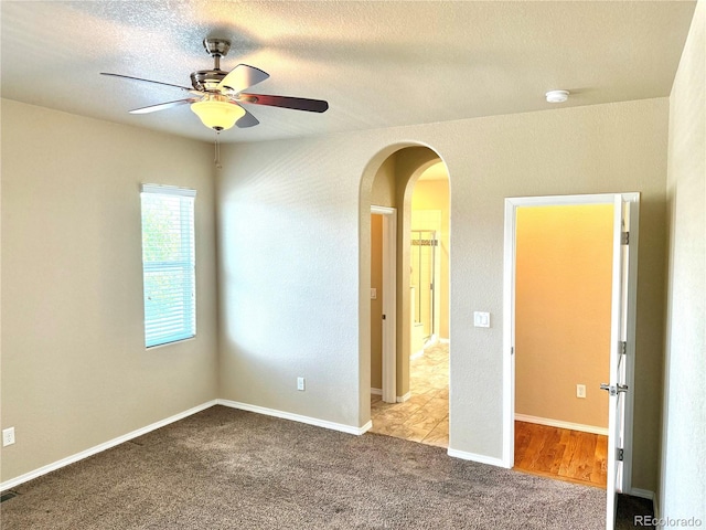 8913 Sunstone Dr, Colorado Springs, CO 80924 - empty room with arched walkways, a ceiling fan, carpet flooring, and a textured ceiling