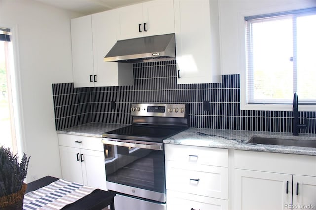 kitchen with plenty of natural light, stainless steel range with electric cooktop, range hood, and white cabinets