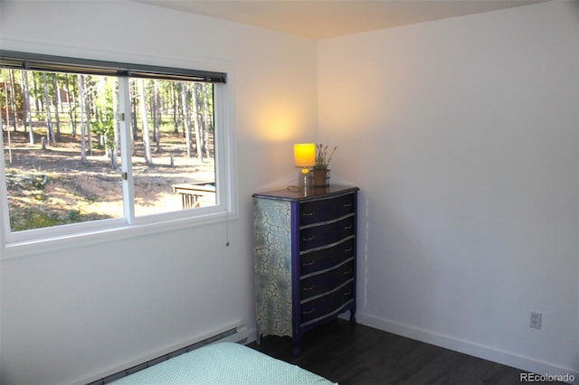 unfurnished bedroom with multiple windows, dark hardwood / wood-style floors, and a baseboard radiator