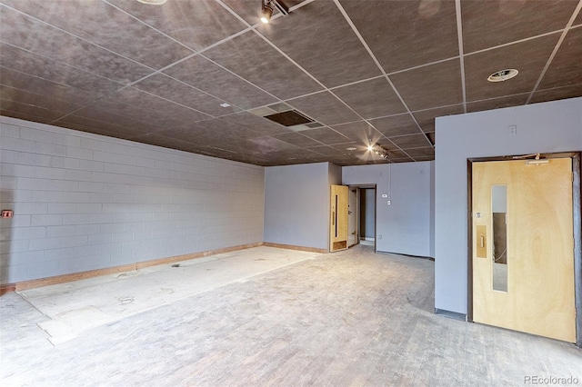 unfurnished room with concrete block wall and wood finished floors