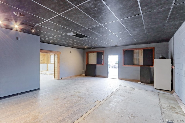 spare room with wood finished floors, concrete block wall, and baseboards