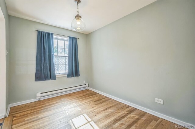 2858 Jasmine St, Denver, CO 80207 - spare room featuring a baseboard heating unit, baseboards, and wood finished floors