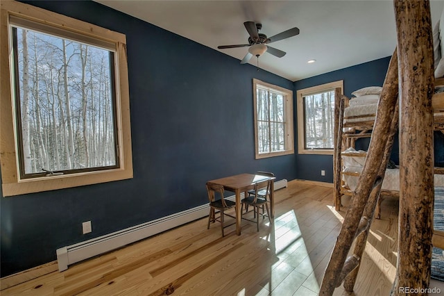 dining area with a ceiling fan, a baseboard radiator, baseboards, and wood finished floors