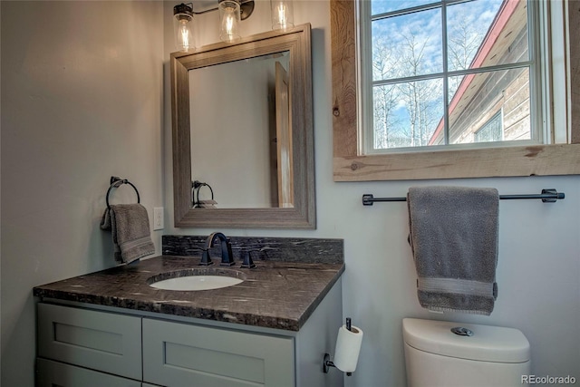 half bath featuring vanity and toilet