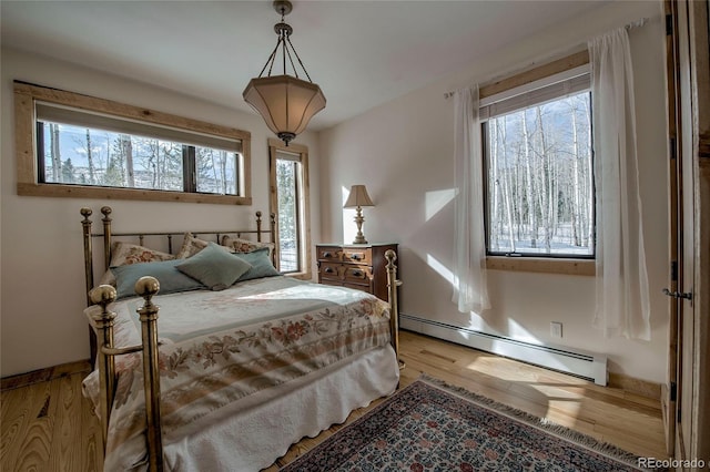 bedroom with a baseboard heating unit and light wood-style floors