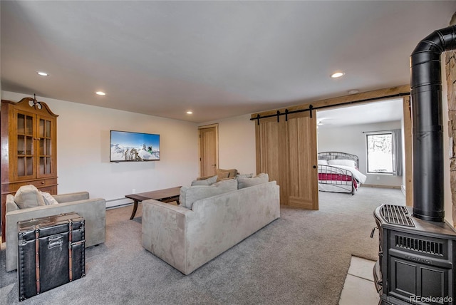 living area featuring recessed lighting, light colored carpet, a barn door, a wood stove, and baseboards