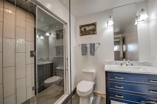 bathroom with toilet, vanity, baseboards, tile patterned floors, and a stall shower