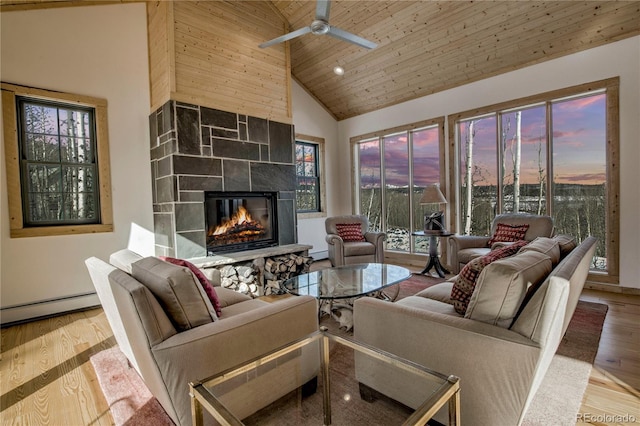 living room featuring high vaulted ceiling, wooden ceiling, a tile fireplace, wood finished floors, and baseboard heating