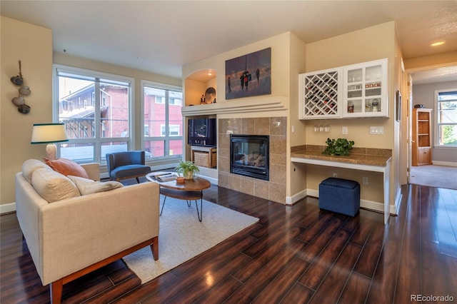 living area with wood finished floors, baseboards, and a tile fireplace