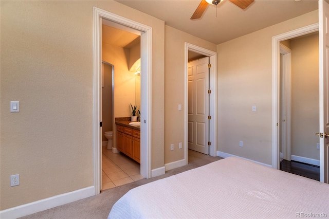 bedroom featuring ensuite bath, a ceiling fan, baseboards, and light carpet