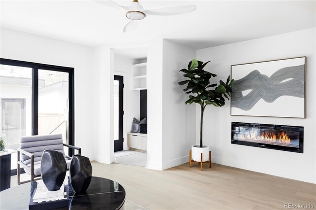 425 S Pearl St, Denver, CO 80209 - living area featuring a glass covered fireplace, light wood-style floors, ceiling fan, and baseboards