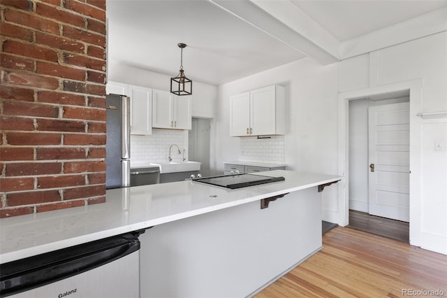 7801 Valley View St, Louviers, CO 80131 - kitchen with tasteful backsplash, pendant lighting, white cabinetry, black electric cooktop, and light wood-style floors