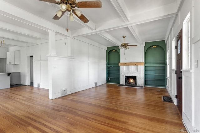 7801 Valley View St, Louviers, CO 80131 - unfurnished living room featuring a ceiling fan, a decorative wall, wood finished floors, a fireplace, and beam ceiling