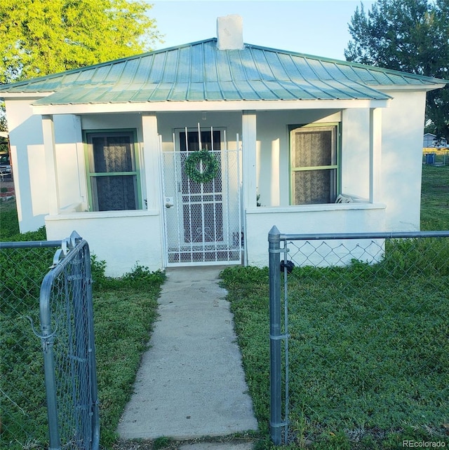 511 N Petroleum Ave, Florence, CO 81226 - view of front of property with a standing seam roof, a gate, metal roof, stucco siding, and a porch