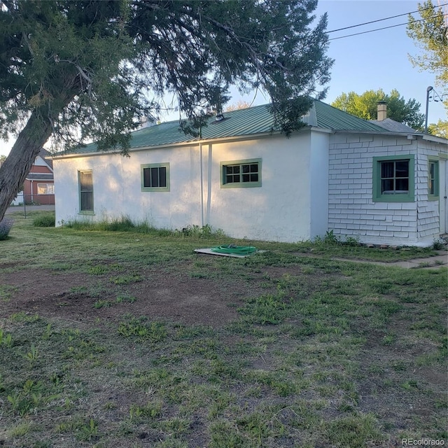 511 N Petroleum Ave, Florence, CO 81226 - view of side of home with a chimney, metal roof, and stucco siding