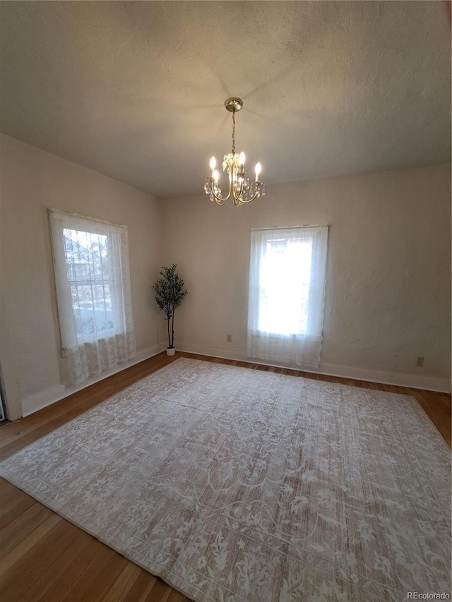 511 N Petroleum Ave, Florence, CO 81226 - empty room featuring wood finished floors, a chandelier, baseboards, and a textured ceiling