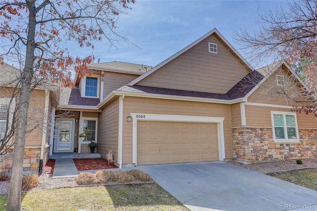 view of front of house with stone siding, a garage, driveway, and roof with shingles