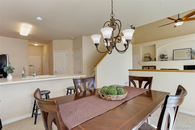 dining room featuring baseboards, light colored carpet, and ceiling fan with notable chandelier