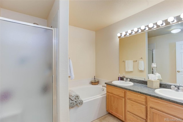 full bathroom featuring a shower stall, double vanity, a garden tub, and a sink