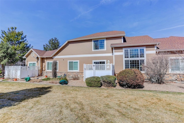 view of front of property featuring stone siding, fence, and a front lawn