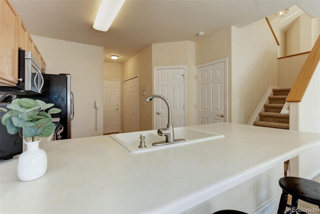 kitchen with light countertops, a breakfast bar area, appliances with stainless steel finishes, and a sink
