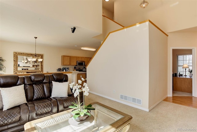 living area with light carpet, an inviting chandelier, baseboards, and visible vents