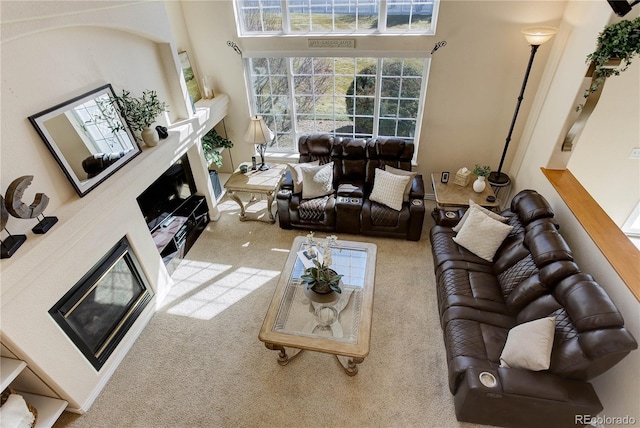 carpeted living room featuring a fireplace and a high ceiling
