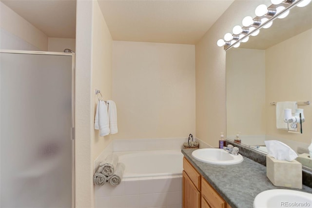 full bath featuring double vanity, a garden tub, a sink, and a stall shower