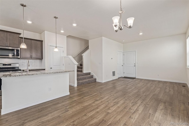 21821 E 7th Ave, Aurora, CO 80018 - kitchen with appliances with stainless steel finishes, wood finished floors, tasteful backsplash, dark brown cabinetry, and open floor plan