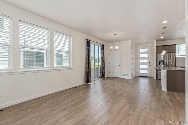 21821 E 7th Ave, Aurora, CO 80018 - unfurnished living room featuring a chandelier and light wood-type flooring