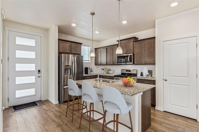 21821 E 7th Ave, Aurora, CO 80018 - kitchen with appliances with stainless steel finishes, dark brown cabinetry, a kitchen breakfast bar, light wood-type flooring, and recessed lighting