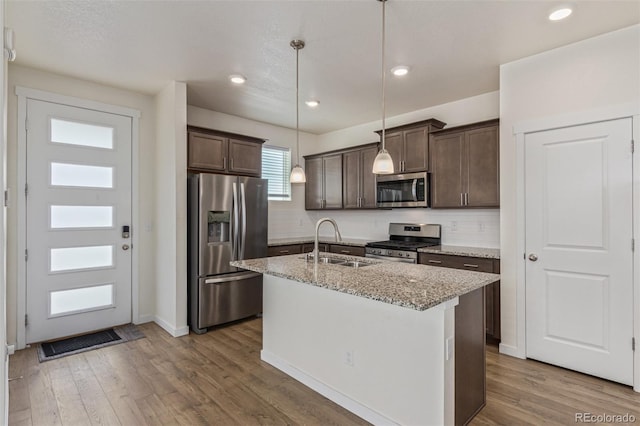 21821 E 7th Ave, Aurora, CO 80018 - kitchen with stainless steel appliances, dark brown cabinetry, backsplash, wood finished floors, and light stone countertops