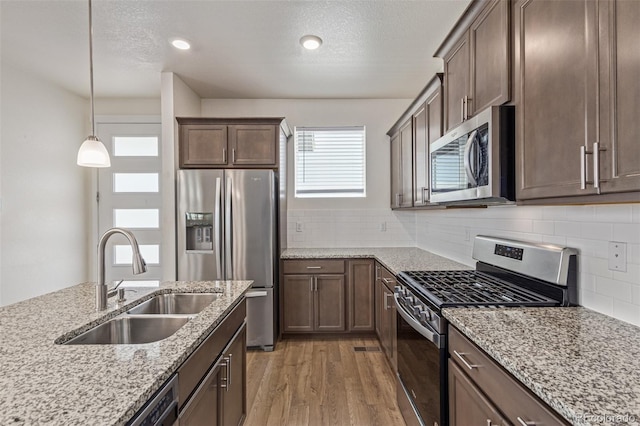 21821 E 7th Ave, Aurora, CO 80018 - kitchen with appliances with stainless steel finishes, light wood-type flooring, light stone counters, decorative backsplash, and a textured ceiling