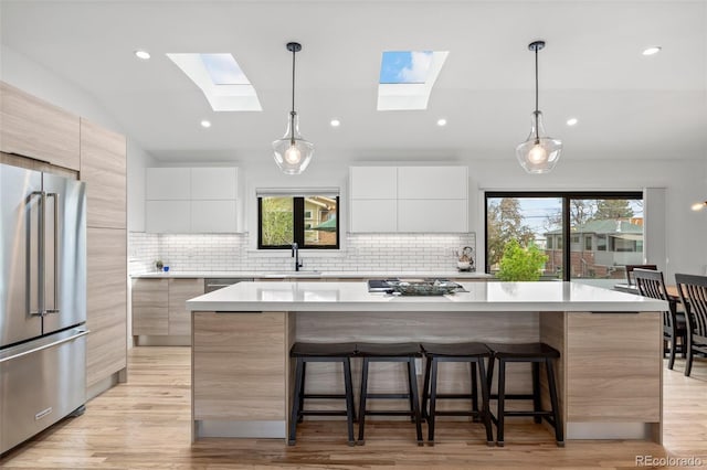 kitchen with a sink, modern cabinets, a kitchen breakfast bar, and high quality fridge