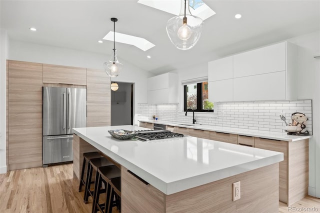 kitchen with appliances with stainless steel finishes, a sink, decorative backsplash, a kitchen island, and modern cabinets